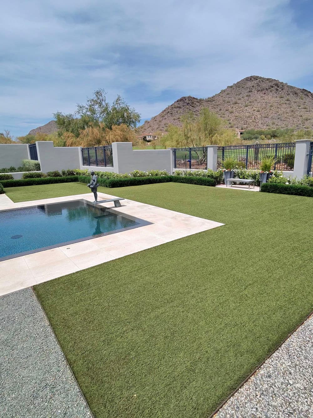 Modern backyard with a pool, landscaped greenery, and mountain scenery in the background.